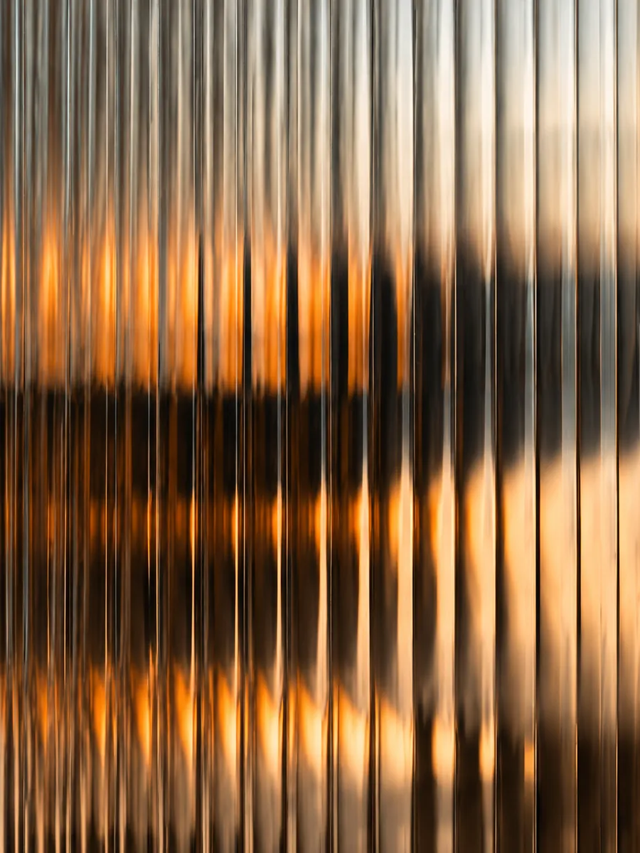 Warm light and shadow behind fluted glass